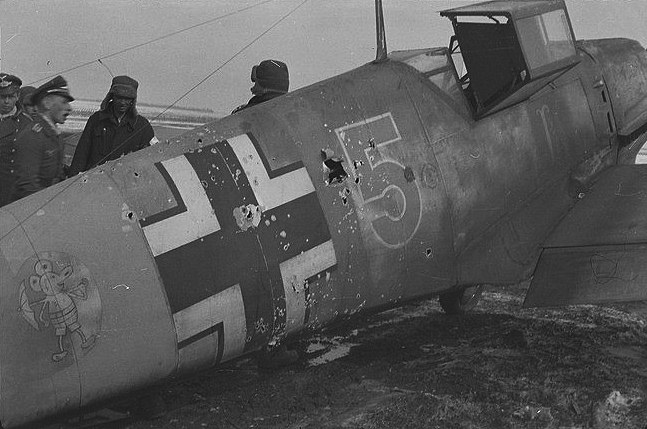 Bf 109 E, Lehrgeschwader 2, I. (J) Gruppe, 3. Staffel, Deutschland, braune 5, Die Maschine hat starke Beschussschäden am Rumpf. Beachte die Art der Antenne…